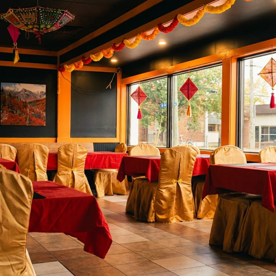 Restaurant dining room with red tablecloths, gold chair covers, and decorative lanterns by large windows.