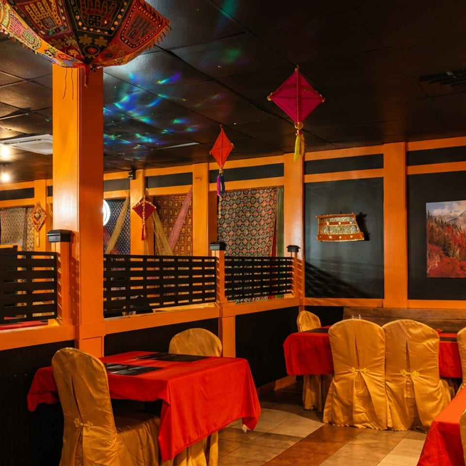Vibrant restaurant dining area with orange and black decor, red tablecloths, and decorative lanterns.