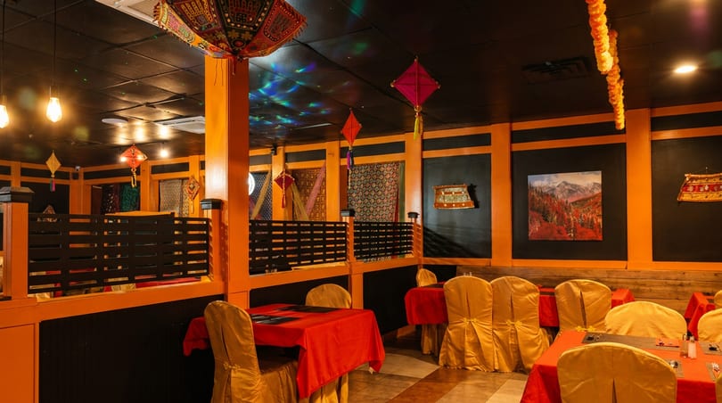 Vibrant restaurant dining area with orange and black decor, red tablecloths, and decorative lanterns.
